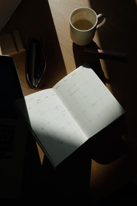 Open planner and coffee for planning how often contractors post on social media